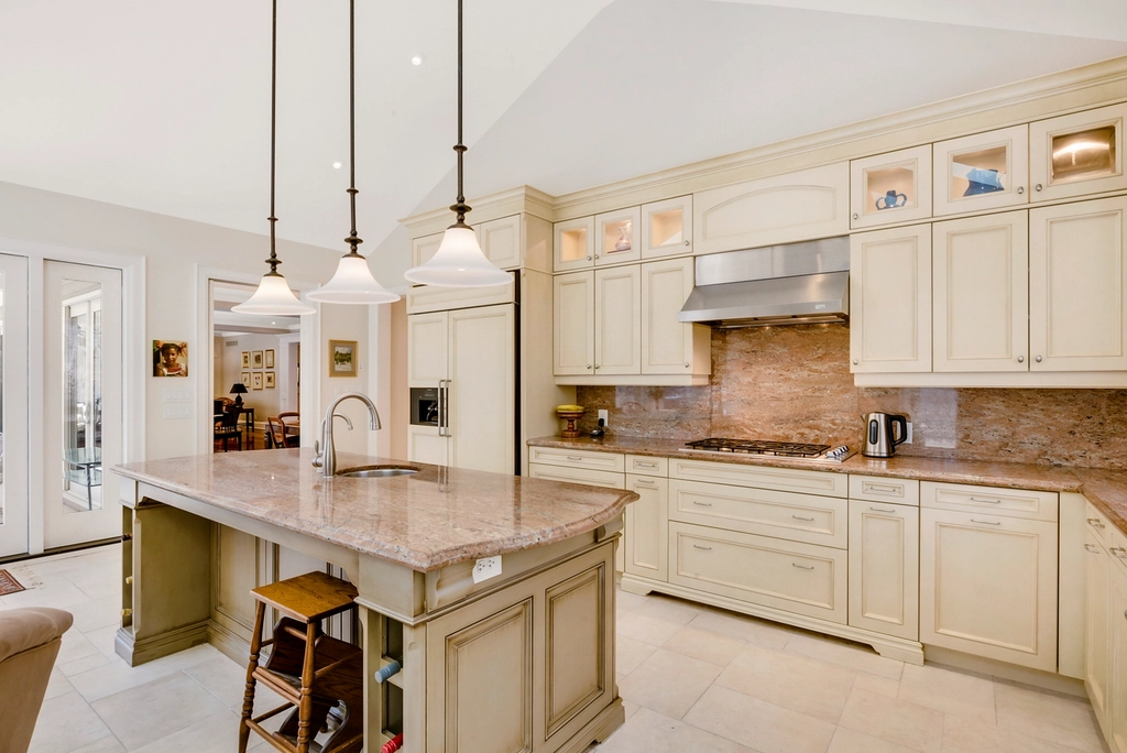 Bright kitchen with cream cabinetry, glass-front uppers and a large island with seating